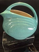 Front side of turquoise Red Wing handled planter bowl on acrylic stand