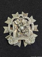 Front view of silver-plated Via Crucis badge showing inscriptions and relief detail