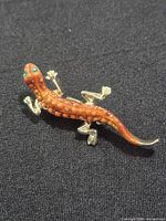 Full brooch on fabric background showing gecko shape and color