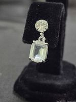 front view showing round and emerald-cut stones on earring