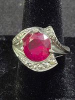 Front view showing red gemstone and leaf-shaped setting