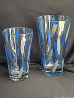 Two clear glass vases with blue leaf design side by side