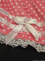 Close view of hem showing lace trim, satin ribbon bands, and bow