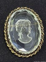 Front view of oval glass cameo brooch in gold-plated setting