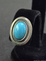 Front view of one earring showing turquoise cabochon and silver-tone bezel