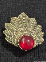Front of gold-tone fan brooch with red cabochon