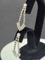 Pair of rhinestone gold-tone dangle earrings on display stand