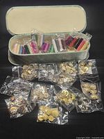 Open sewing box with multiple bags of gold-tone buttons and spools of thread