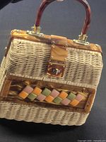 Full view of wicker handbag showing trim, handle and clasp