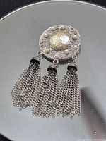 Full view of pendant showing central imitation pearl, surrounding seed pearls and three chain tassels