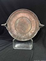 Front view of round silver-plated tray showing hammered center and pierced rim