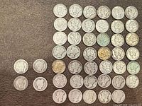 Full lot of Barber and Mercury dimes laid out on surface