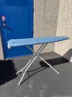 Ironing board standing unfolded showing full frame and cover