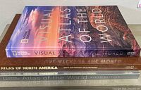 Three stacked atlases showing spines and covers