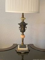 Full view of lamp showing urn brass body, marble accents, square marble pedestal and pleated shade