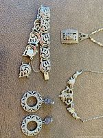 Group shot of bracelet, pendant necklace, scroll necklace and earrings
