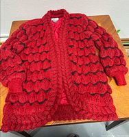 Full front view of red bubble knit cardigan laid flat