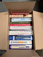 Box of stacked health and wellness books showing titles