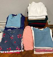 Folded stacks of slacks and tops on table