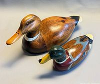 Both wooden mallard figurines side by side, showing size difference and finishes