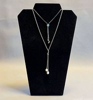 Both necklaces displayed on black stand showing overall style and drop elements