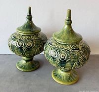 Front angled view of both matching green ceramic covered vessels