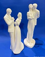 Both Royal Doulton white porcelain figurines standing together against blue backdrop