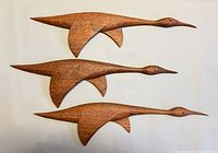 Front view of three carved wood birds, showing shape and color