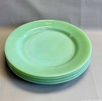 Stack of four jadeite green plates, side view shows smooth rims and color