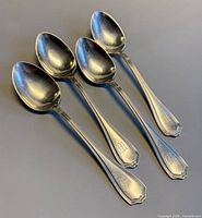 Four Birks sterling silver tablespoons laid out, bowl ends at top