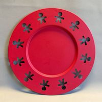 Front view of red Alessi tray showing cutout figures