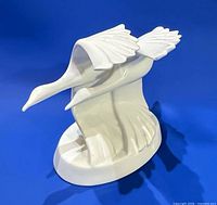 Front view of white glazed porcelain figurine of three geese in flight on oval base