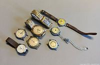 All nine watches laid out displaying cases, dials and two expansion bracelets