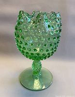 Front view of green hobnail footed vase