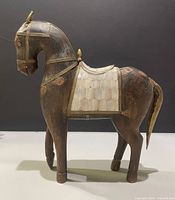 Full left-side view of carved wood horse with brass and mother-of-pearl details