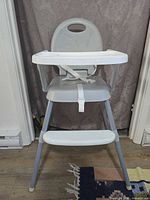 Full front view of highchair showing tray, straps, footrest, legs