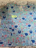 Front view of scrub top showing overall design, print, pockets and size note