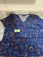 Full view of the scrub top laid flat showing pattern and pockets