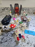 Overview of lot showing CommTech reader, action figure in capsule, multiple Dalmatian figurines, robot part, grey accessory, trading card pack