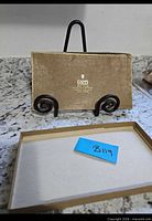 Gold-tone Gucci box lid on stand with base tray below