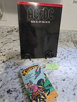 Front covers of AC/DC Back in Black songbook and Superman comic