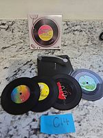 Full set: four coasters, holder, box visible