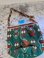Front view of woven canvas shoulder bag showing pattern, strap and tassels