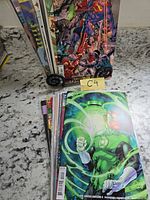 Stack of fifteen comic books showing cover of The Green Lantern #4 and group shot cover of assorted Marvel heroes