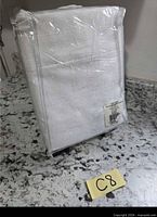 Sealed package showing folded white curtain panel