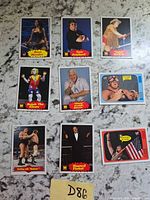 Nine WWF wrestling trading cards laid out on speckled surface, sticky note marked D86 visible