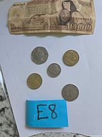 Paper banknote and five coins displayed on white background