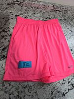 Front view of neon pink Champion girls shorts