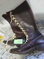 Side view of both tall brown leather boots showing lacing and overall condition