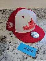 Full view of red and white New Era BC Lions snapback hat with maple leaf front design and sticker